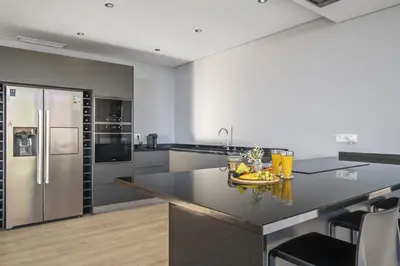 a kitchen with stainless steel appliances and a black counter top at Villa Elysian Oasis by Homie in Fajã da Ovelha