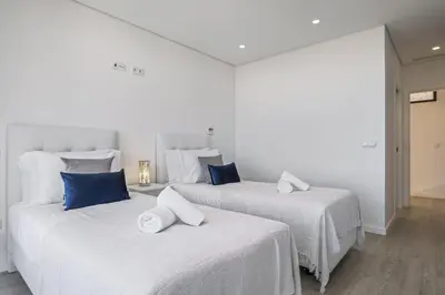 two white beds with blue pillows in a room at Villa Elysian Oasis by Homie in Fajã da Ovelha