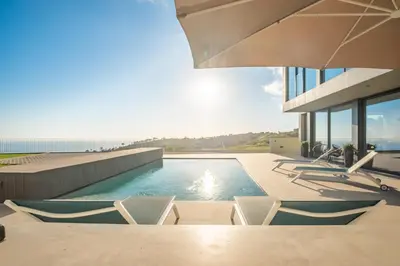a swimming pool with chairs on a house at Villa Elysian Oasis by Homie in Fajã da Ovelha