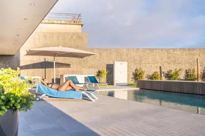 a woman laying on a chair next to a pool at Villa Elysian Oasis by Homie in Fajã da Ovelha