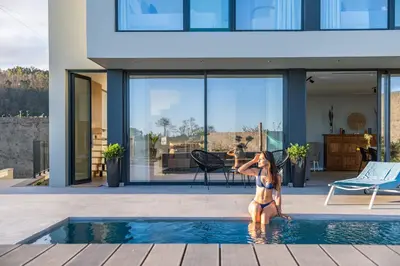 a woman in a bikini sitting in a swimming pool at Villa Elysian Oasis by Homie in Fajã da Ovelha