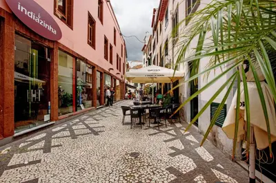 an empty street with tables and umbrellas in a city at Família Dória Nóbrega T0 in Funchal