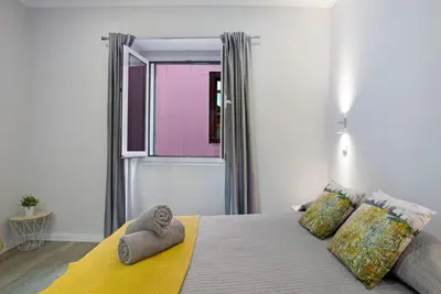 a bedroom with a bed with a yellow blanket and a window at Família Dória Nóbrega T0 in Funchal