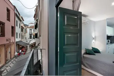 a green door in a room with a bed on a balcony at Família Dória Nóbrega Estúdio in Funchal