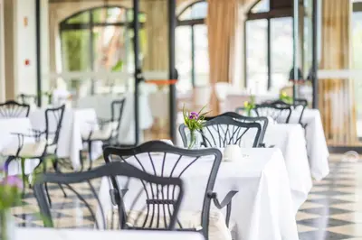 a row of tables and chairs with white tables and flowers at Quinta Funchal Gardens - Adults Only in Funchal
