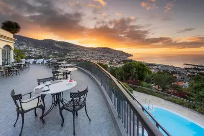a balcony with tables and chairs and a view of the city at Quinta Funchal Gardens - Adults Only in Funchal