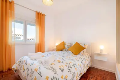 a bedroom with a bed with yellow pillows and a window at Casa Cintra in Almádena