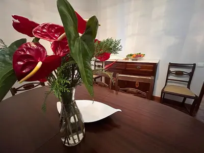 a vase with red flowers sitting on a table at Vila Pico da Torre Apartment in Câmara de Lobos
