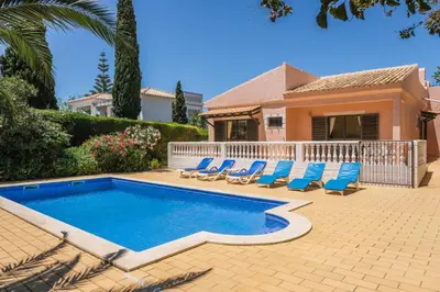 a swimming pool with chairs and a house at Vila Telo in Luz