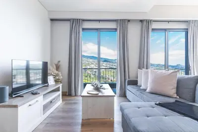 a living room with a tv and a large window at Figueiras House by Atlantic Holiday in Câmara de Lobos