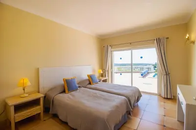 a bedroom with two beds and a large window at Parque da Floresta villa 209 with pool on golf resort in Budens