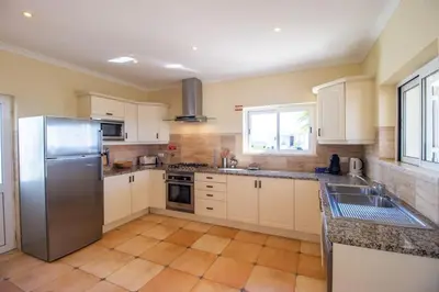 a kitchen with white cabinets and a stainless steel refrigerator at Parque da Floresta villa 209 with pool on golf resort in Budens