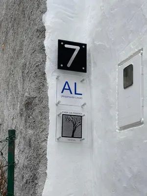 a sign on the side of a white wall with aocl at Casa da Figueira - Guest House in Figueira