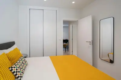 a bedroom with a bed with a yellow blanket and a mirror at Golden City by An Island Apart in Funchal