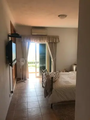 a bedroom with a bed and a television and a window at Villa das Acacias Praia da Luz beautiful 3 bedroom villa with sea views in Luz
