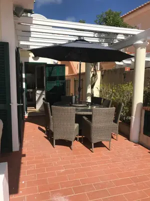 a table and chairs under an umbrella on a patio at Villa das Acacias Praia da Luz beautiful 3 bedroom villa with sea views in Luz