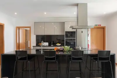 a kitchen with a black island with bar stools at Germana House by An Island Apart in Ponta do Sol