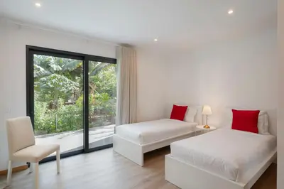 a bedroom with two beds and a chair and a window at Germana House by An Island Apart in Ponta do Sol