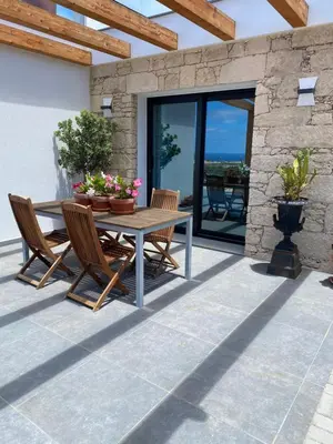 a patio with a wooden table and chairs at B&B Camacha Porto Santo in Porto Santo