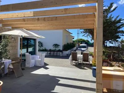 a patio with tables and chairs and an umbrella at B&B Camacha Porto Santo in Porto Santo