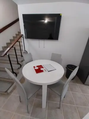 a white table with chairs and a tv on a wall at Villa Supranee Paradise in Câmara de Lobos