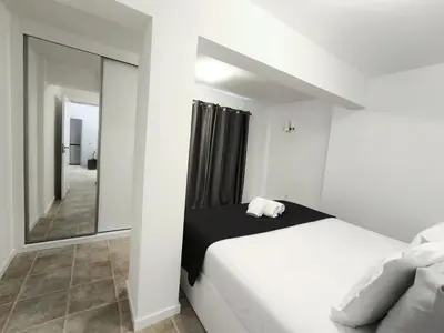 a bedroom with a white bed and a mirror at Villa Supranee Paradise in Câmara de Lobos