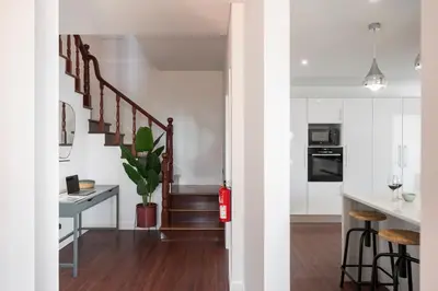 a kitchen with white walls and a staircase with a table at Casa das Maravilhas by An Island Apart in Câmara de Lobos