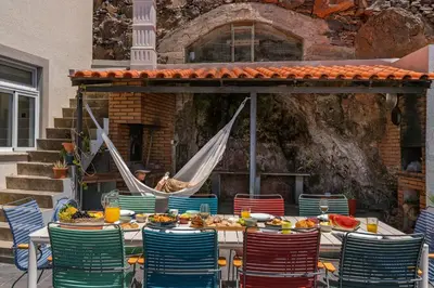 a table with chairs and a hammock with food on it at Casa das Maravilhas by An Island Apart in Câmara de Lobos
