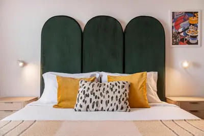 a bed with a green headboard and yellow pillows at Casa das Maravilhas by An Island Apart in Câmara de Lobos