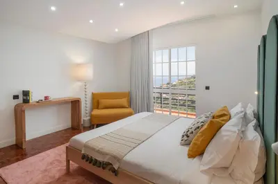 a bedroom with a bed and a window and a chair at Casa das Maravilhas by An Island Apart in Câmara de Lobos