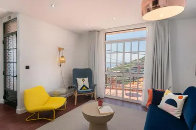 a living room with two chairs and a large window at Casa das Maravilhas by An Island Apart in Câmara de Lobos