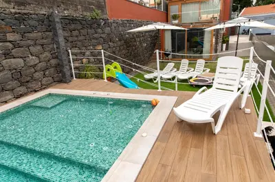 a swimming pool with white chairs and a swimming pool at HOMELIKE FUNCHAL I in Funchal