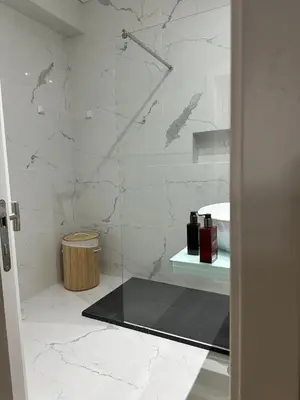 a bathroom with a shower with white marble walls at HOMELIKE FUNCHAL II in Funchal