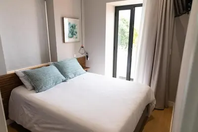 a bedroom with a bed with blue pillows and a window at HOMELIKE FUNCHAL II in Funchal