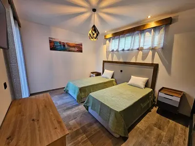 a room with two beds and a table at Casa Requinte - Jacuzzi in Arco da Calheta