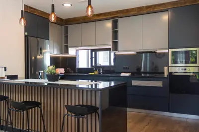 a kitchen with black and white cabinets and stools at Casa Requinte - Jacuzzi in Arco da Calheta