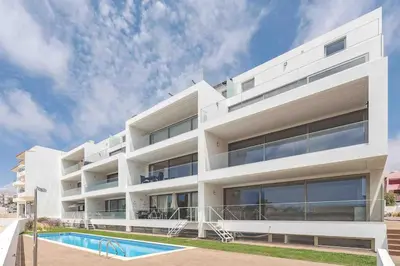 a white apartment building with a swimming pool at Hibisco is a modern apartment, 5min walk to beach in Luz
