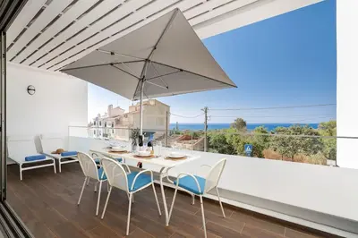 a white table with chairs and an umbrella on a balcony at Hibisco is a modern apartment, 5min walk to beach in Luz