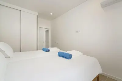 a white room with two beds and a mirror at Hibisco is a modern apartment, 5min walk to beach in Luz