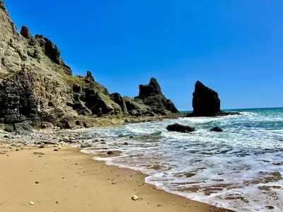 a sandy beach with rocks and the ocean at Hibisco is a modern apartment, 5min walk to beach in Luz