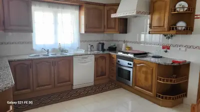 a kitchen with wooden cabinets and a white stove top oven at Casa Estêvão in Aljezur