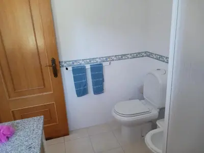 a bathroom with a toilet and two blue towels at Casa Estêvão in Aljezur