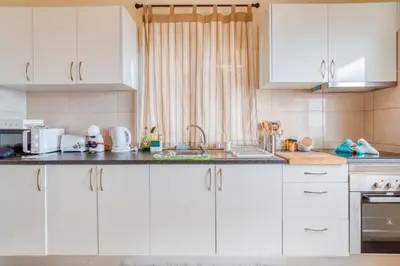 a kitchen with white cabinets and a sink at Cantinho da Portada in Seixal