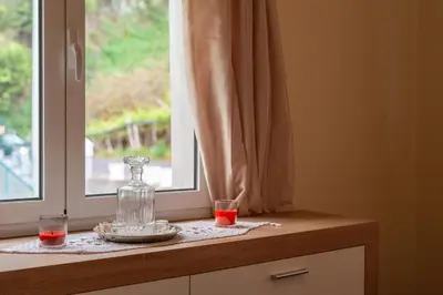 a window with two glasses and a bottle on a counter at Cantinho da Portada in Seixal