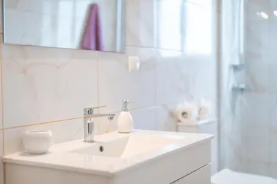 a white bathroom with a sink and a mirror at Cantinho da Portada in Seixal
