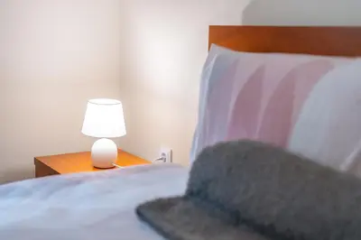a bed with a lamp on a nightstand next to it at Cantinho da Portada in Seixal