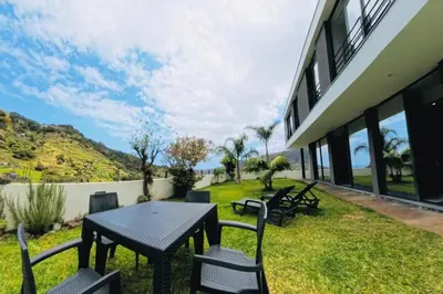a patio with a table and chairs on the grass at Sal e Pimenta House - A Wellbeing Retreat in Machico