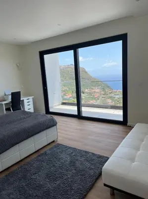 a bedroom with a bed and a large window at Villa Arco Iris in Arco da Calheta