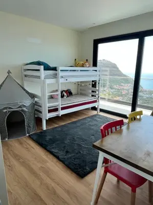 a bedroom with a bunk bed and a table and a tableablish at Villa Arco Iris in Arco da Calheta