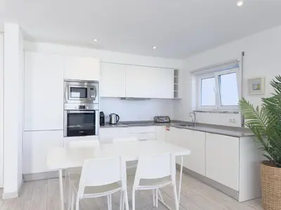 a kitchen with white cabinets and a white table and chairs at Beach Retreat Steps from the Ocean #1953 in Luz